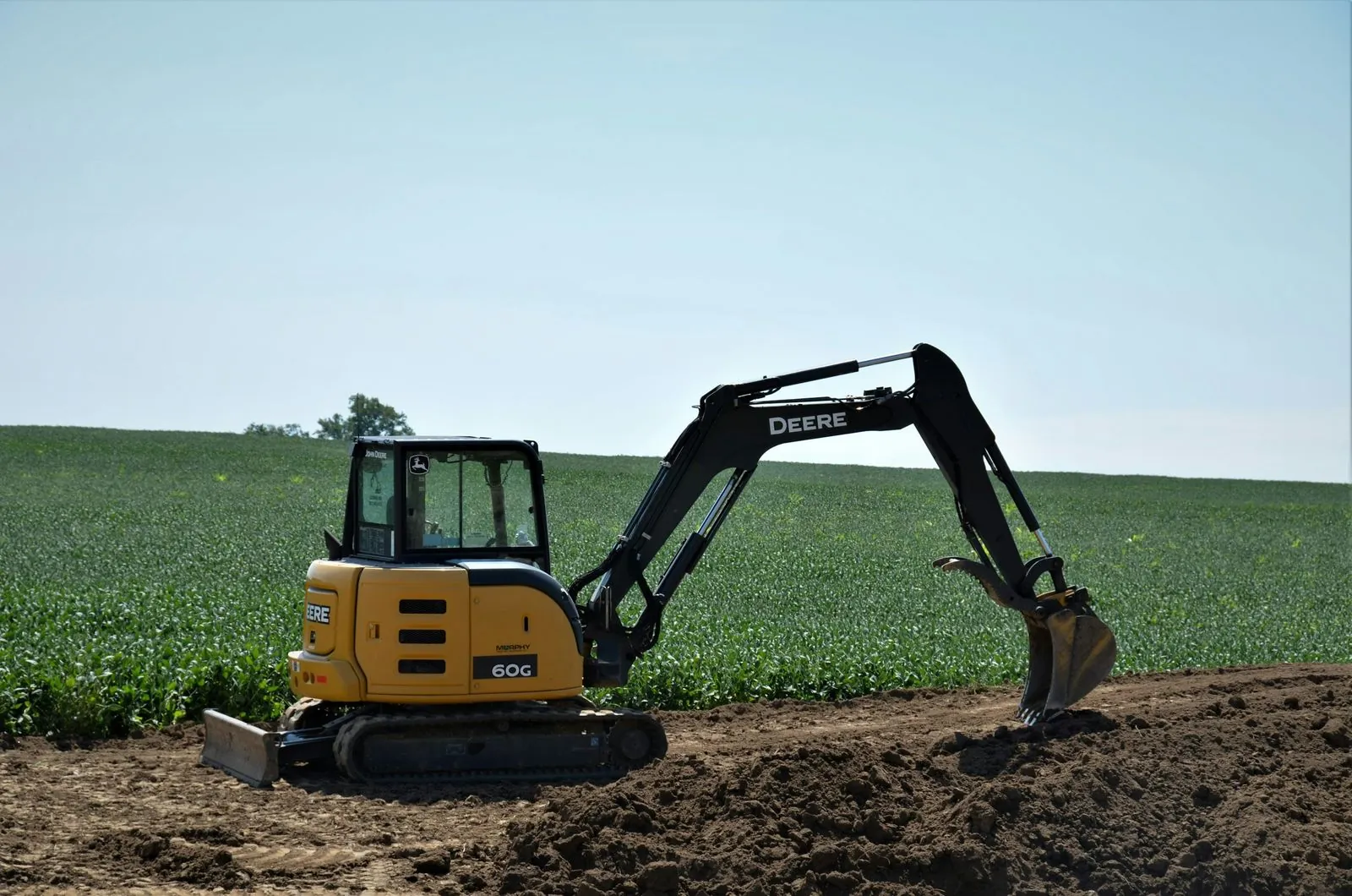 Compact excavator digging on a farm field